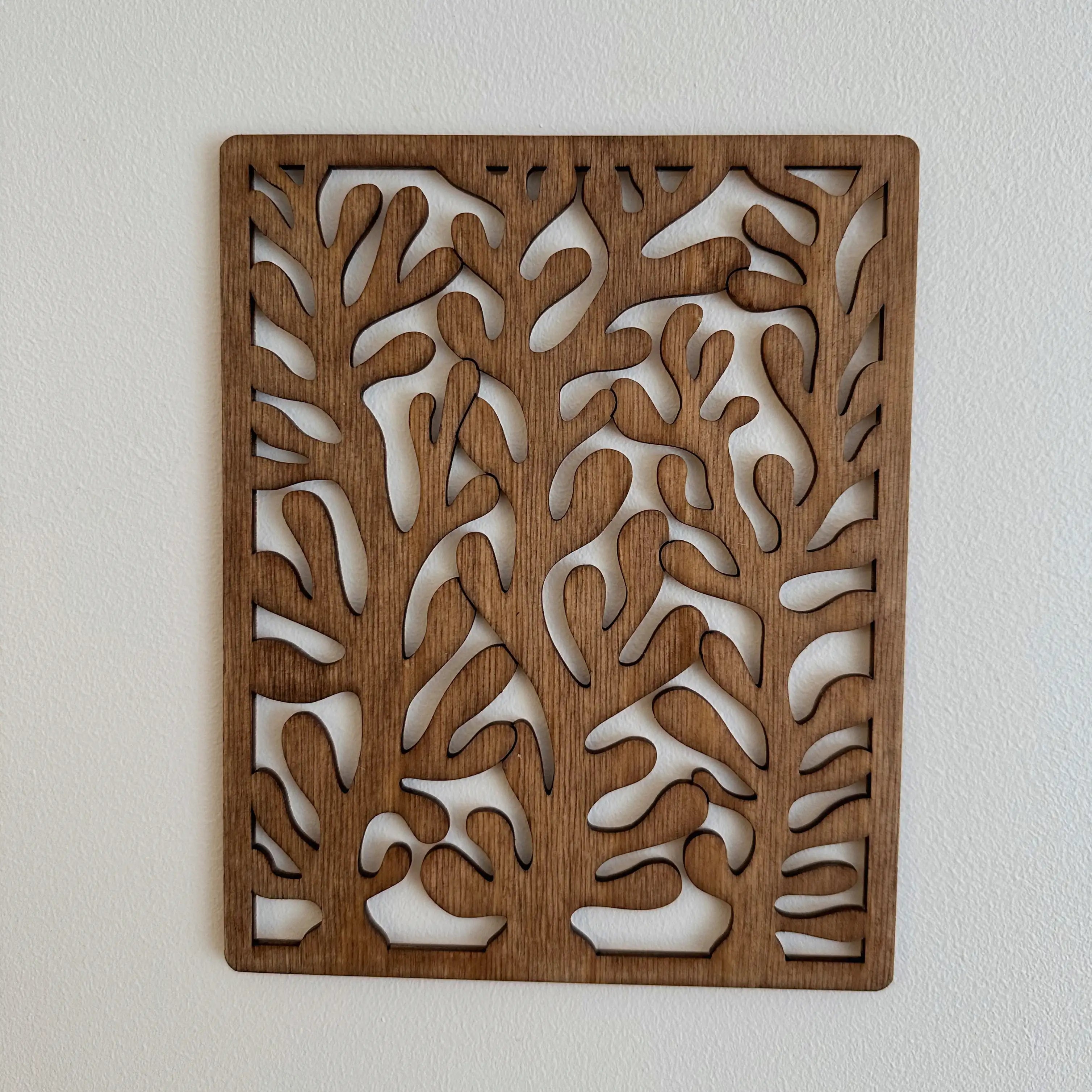 Tableau en bois d'un corail design dans le coloris chêne foncé, accroché sur un mur de chambre. 