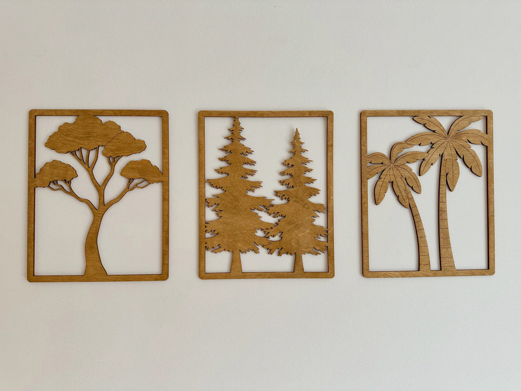 Trois tableaux en bois qui symbolisent chacun un arbre différent, accrochés dans un salon. 