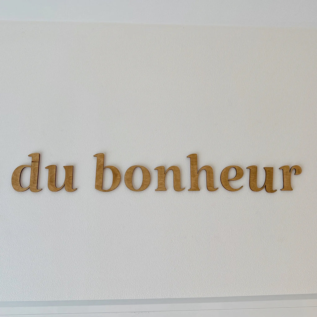 Vue rapprochée sur les mots en bois"du bonheur" accrochés dans une entrée