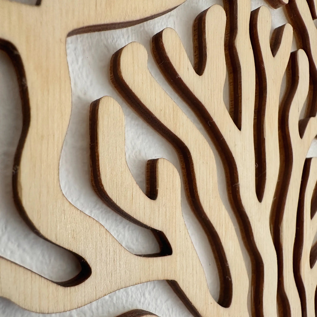Zoom sur un tableau en bois qui représente un corail, accroché sur un mur de salon.