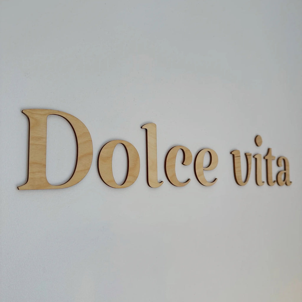 Zoom sur la phrase murale "Dolce vita" sur un mur blanc