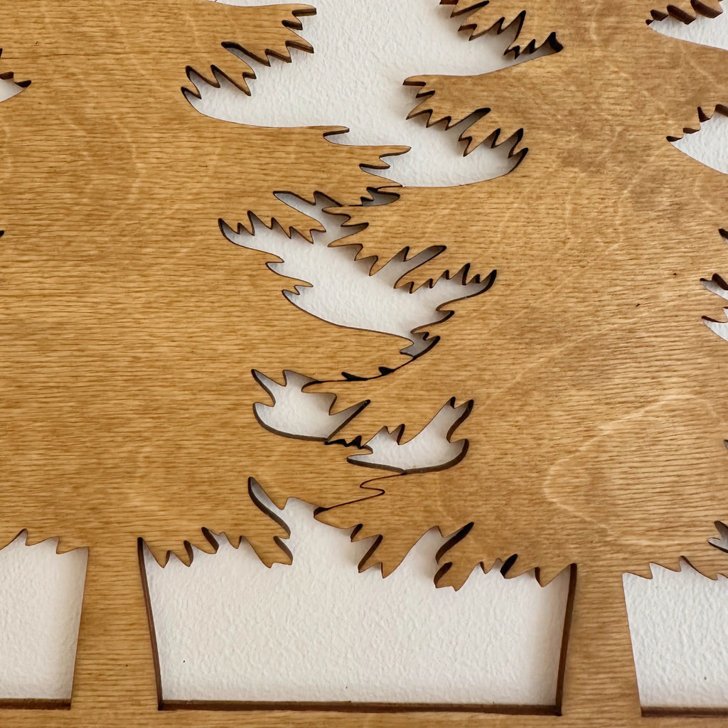 Vue rapprochée d'un tableau en bois qui présente un sapin, décoration moderne et chaleureuse.