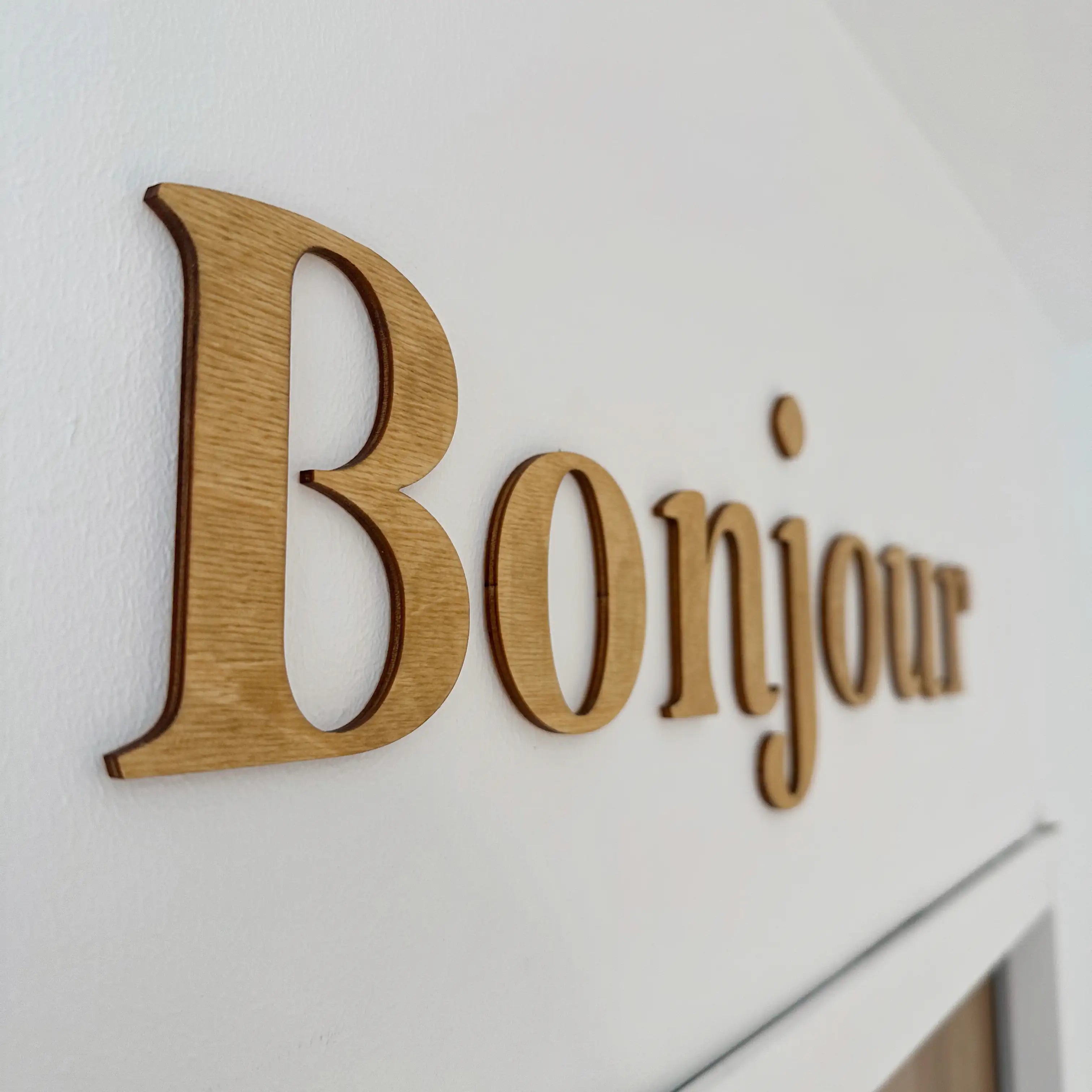 Zoom sur la décoration murale en bois "Bonjour" sur un mur blanc