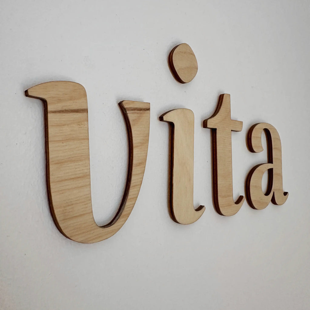 Vue rapprochée sur le mot "Vita" en bois dans le coloris naturel blanc