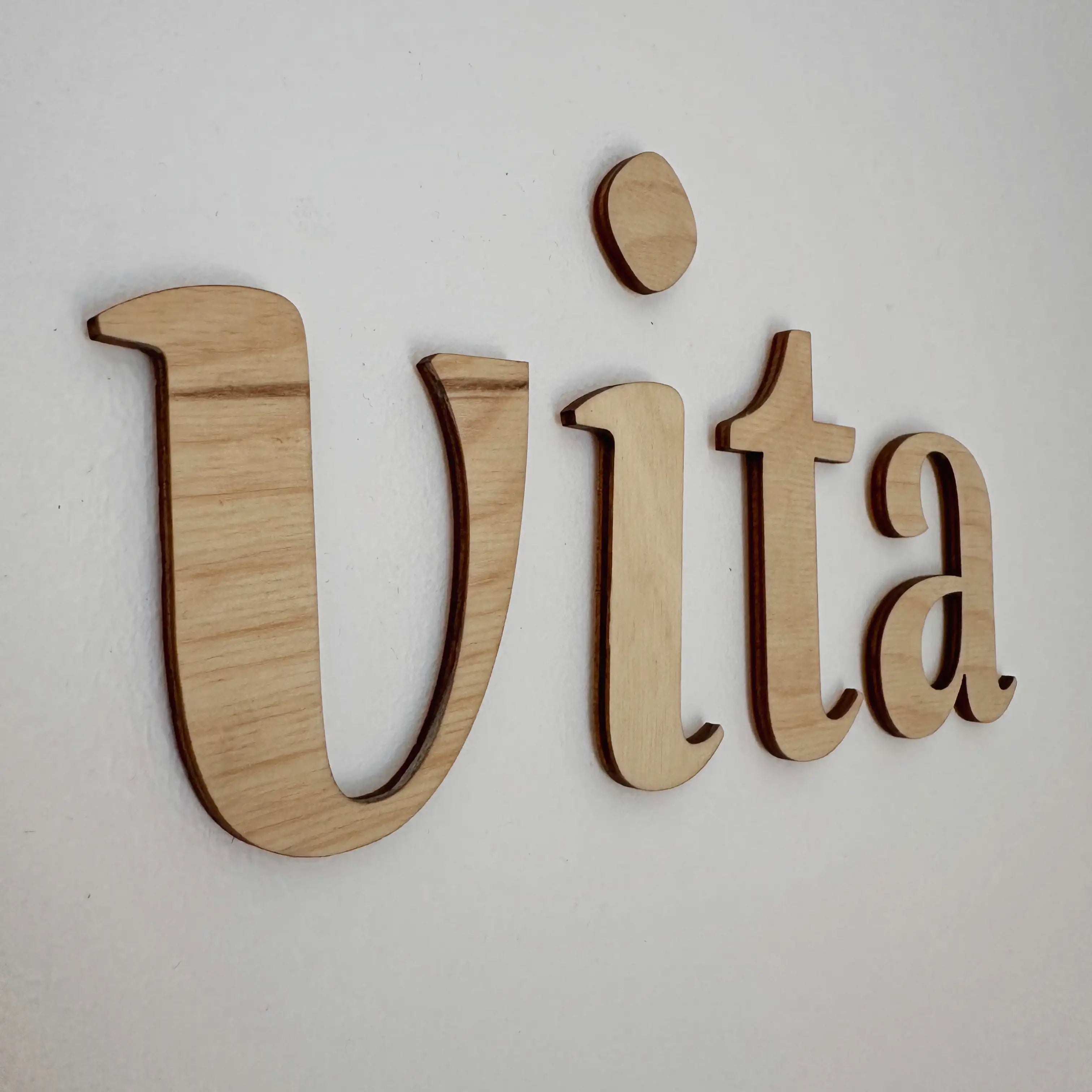 Vue rapprochée sur le mot "Vita" en bois dans le coloris naturel blanc