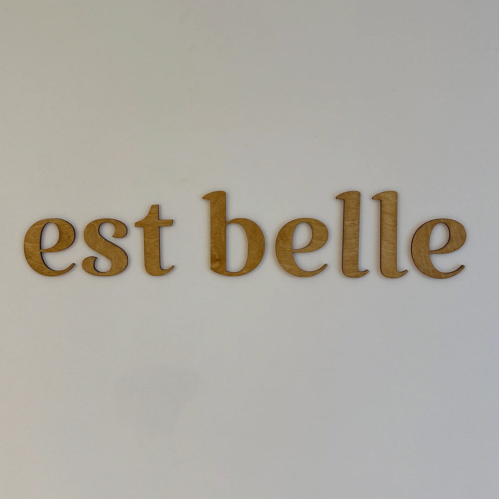 Zoom sur les mots en bois "est belle" accrochés dans une chambre