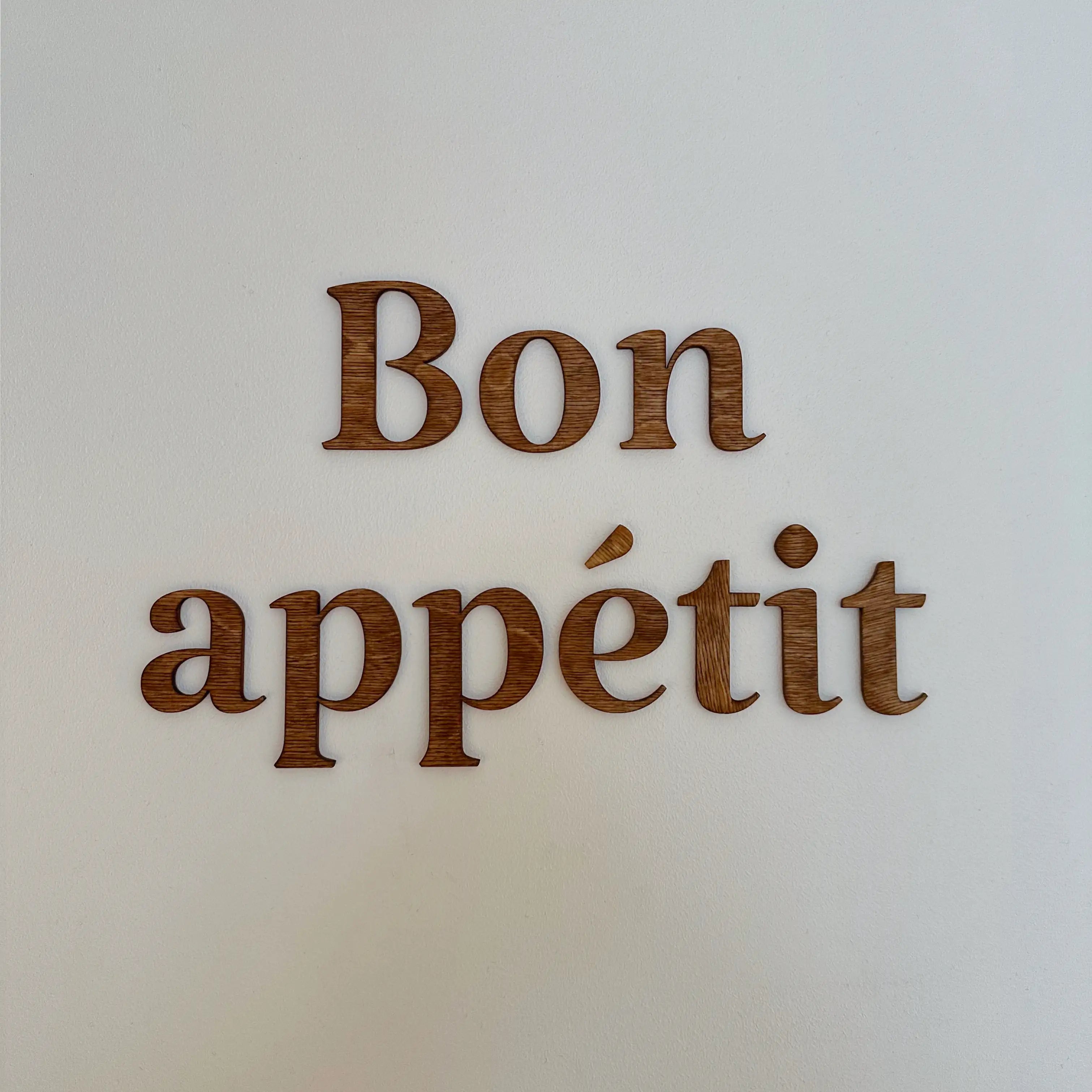 Décoration en bois "Bon appétit" accrochée sur un mur de salle à manger