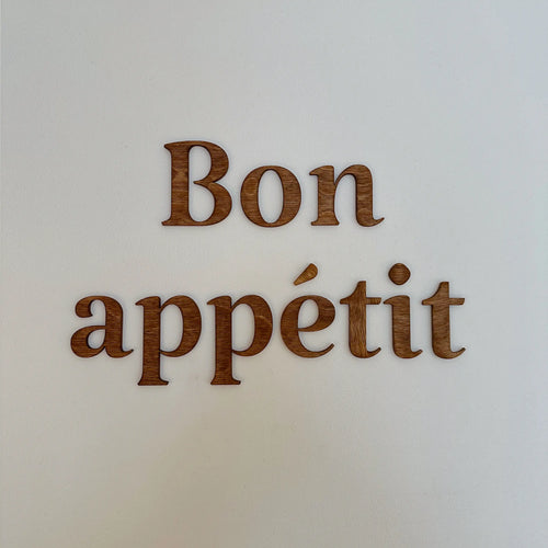 Décoration en bois "Bon appétit" accrochée sur un mur de salle à manger