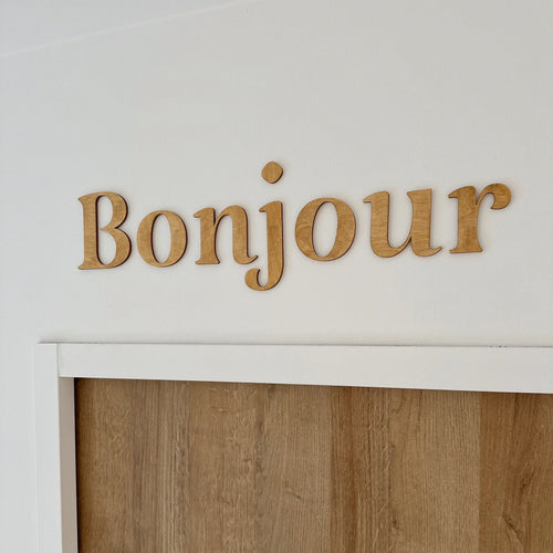 Décoration en bois pour intérieur "Bonjour" accrochée dans un salon
