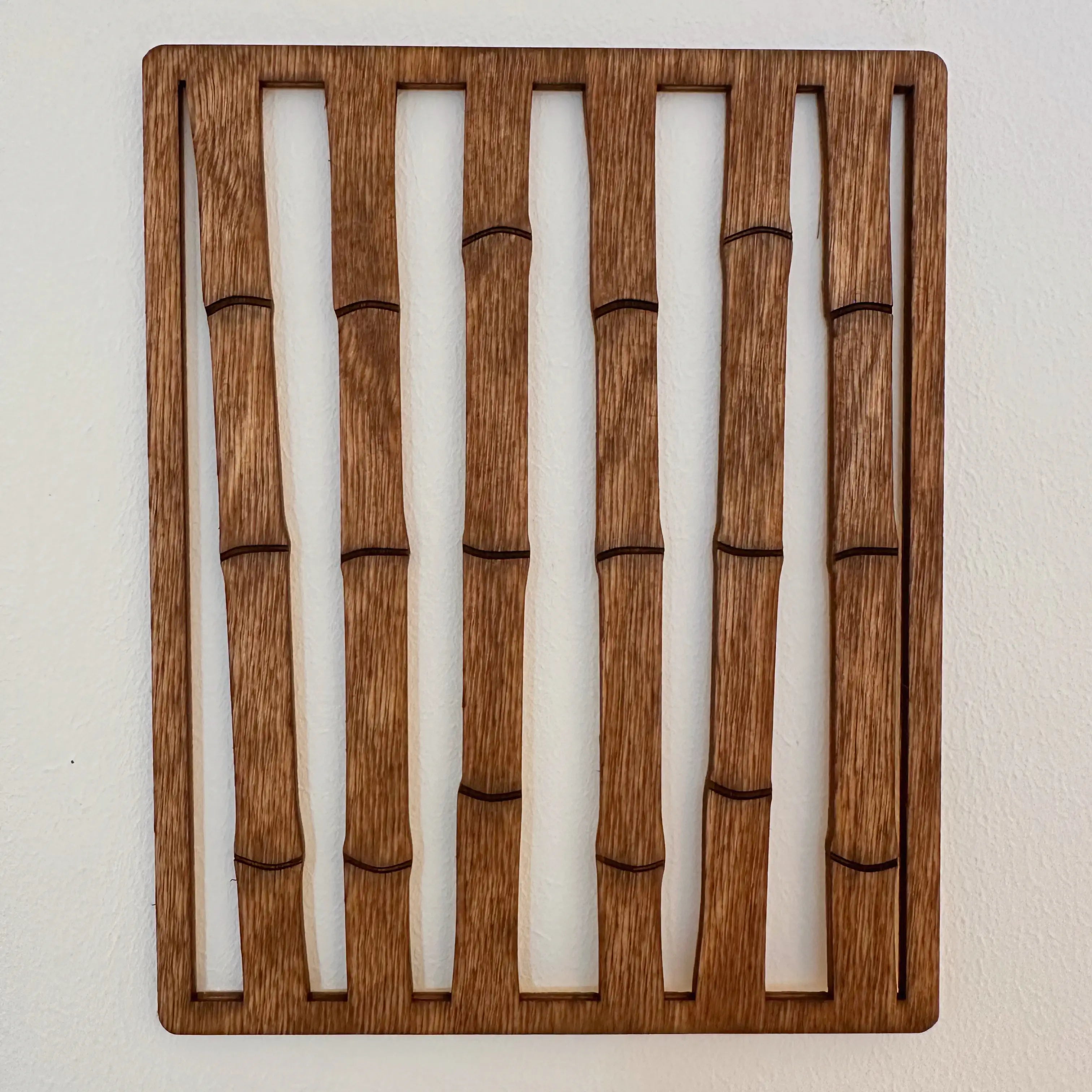 Décoration murale originale qui présente une haie de bambou dans un cadre en bois. 