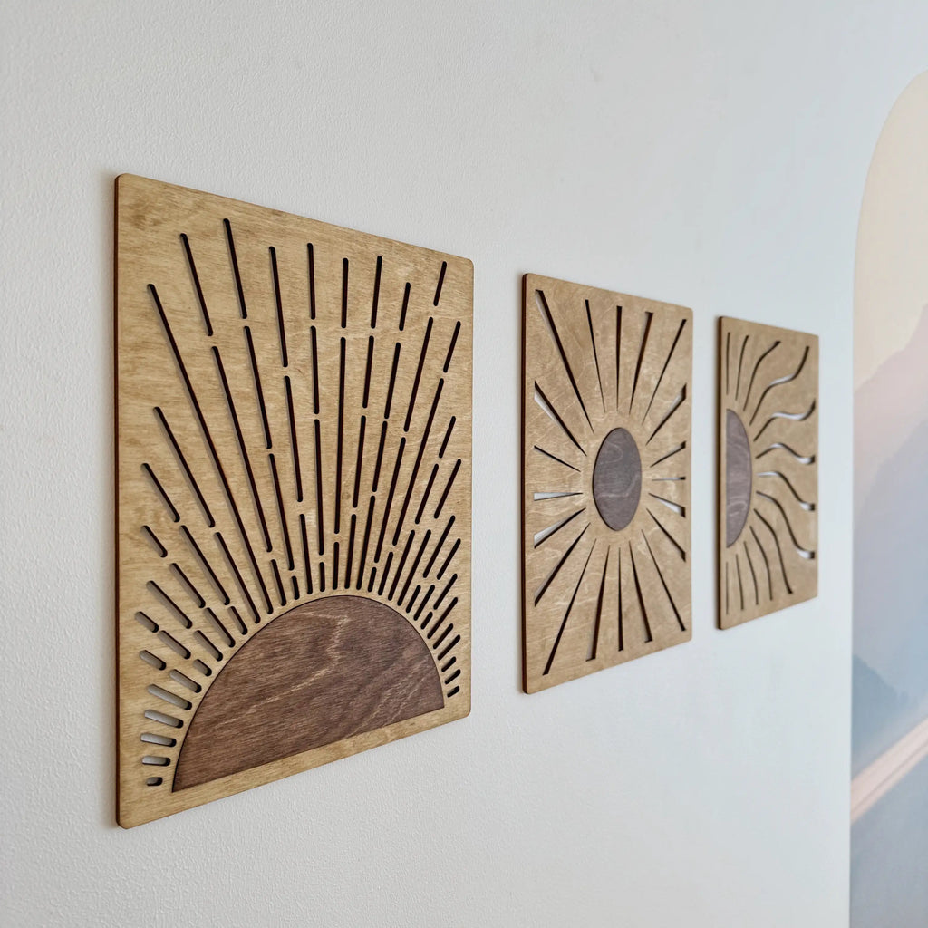 Vue générale des trois tableaux soleil en bois sur un mur blanc