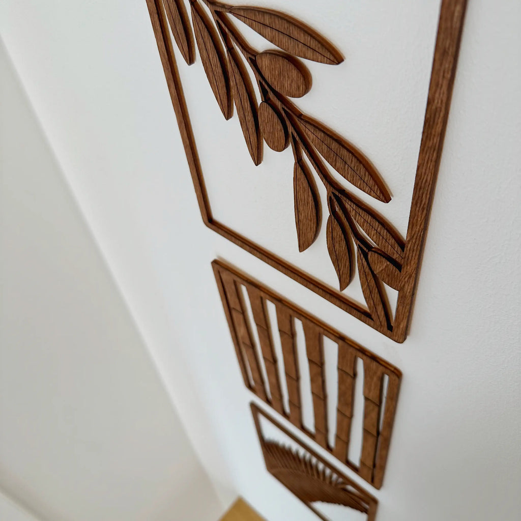 Trois tableaux en bois qui symbolisent un végétal différent, accrochés dans une chambre.