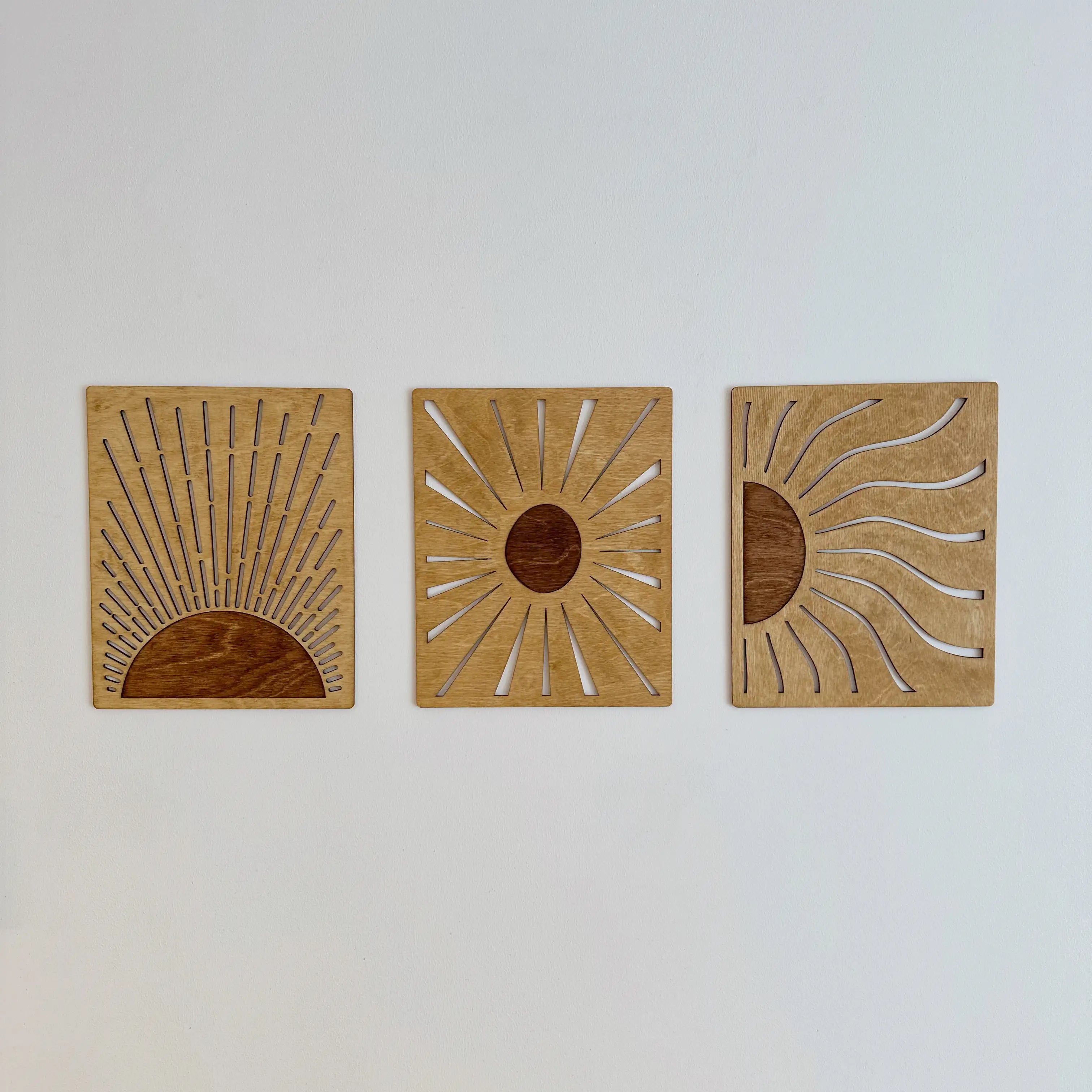 Trois tableaux soleil sur un mur blanc, vue de face, décoration design et chaleureuse.