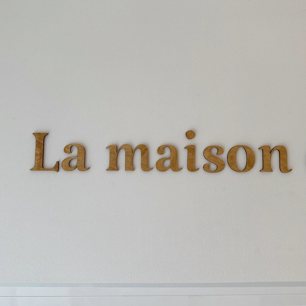 Vue détaillée sur les mots en bois "La maison" sur mur blanc